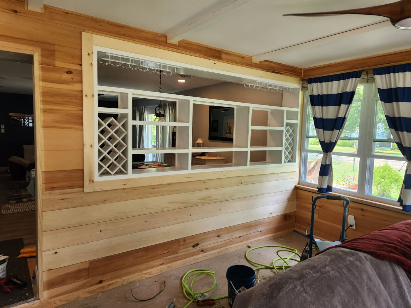 Custom built-in pass-through with lattice wine storage, hanging stemware racks, and open cubby shelving set into a hickory plank wall
