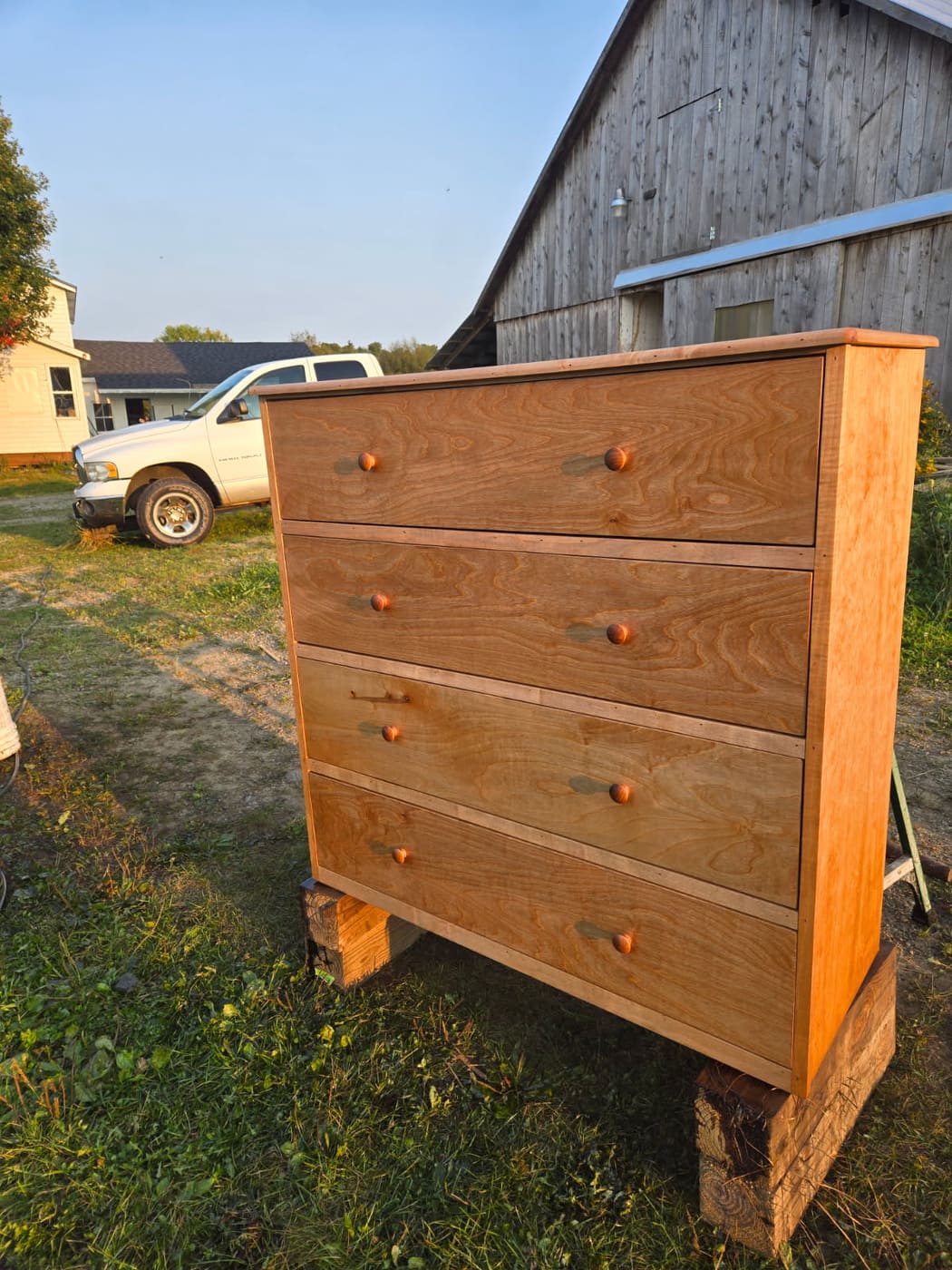 Hand-built maple dresser with four deep drawers and turned wood pulls, standing outside the shop